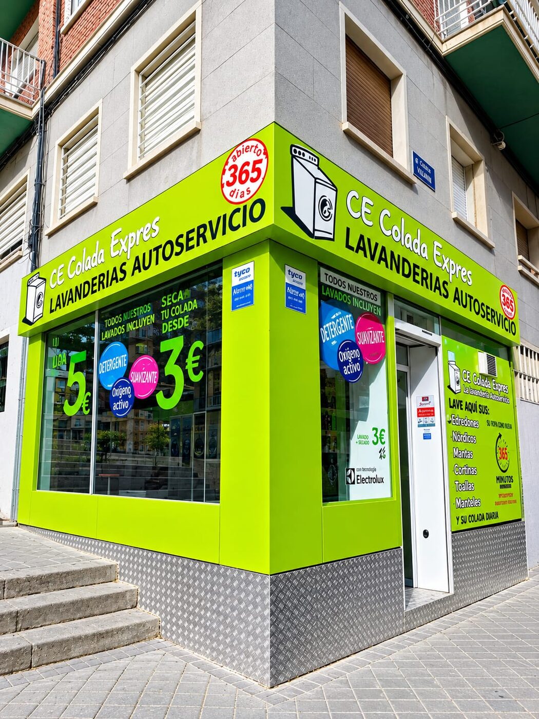 Sala luminosa de Colada Exprés con la fila de lavadoras y secadoras Electrolux y la entrada a la calle